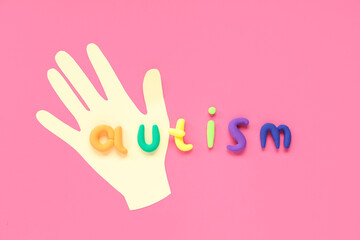 Paper hand and word AUTISM on pink background. Concept of autistic disorder