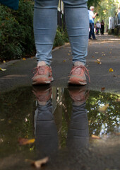 Schuhe einer Weiblichen Person spiegeln sich in einer Pfütze