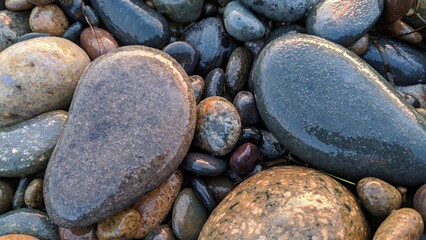 The Melted Rocks of Swamis Beach. Erosion control boulders put down along the shore 50 years ago surrounded by ancient river rocks all in the surf mix at Swamis Reef Surf Park Encinitas California.