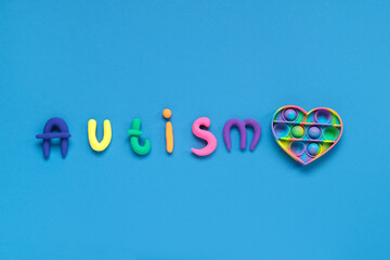 Plasticine word AUTISM and pop it on blue background