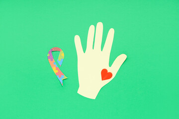 Obraz premium Paper hand, heart and awareness ribbon on green background. Concept of autistic disorder
