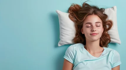 Fotobehang a young woman sleeping on pillow isolated on pastel blue colored background. Girl sleep deeply peacefully rest. Top above high angle view photo portrait of satisfied .senior wear blue shirt © Sittipol 