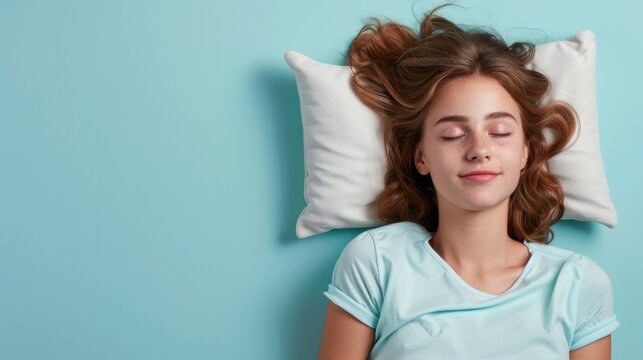 a young woman sleeping on pillow isolated on pastel blue colored background. Girl sleep deeply peacefully rest. Top above high angle view photo portrait of satisfied .senior wear blue shirt