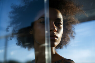 Portrait of a young african american woman looking through window