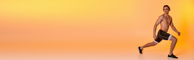 Obraz premium young shirtless man in black shorts exercising actively and looking away on orange backdrop, banner
