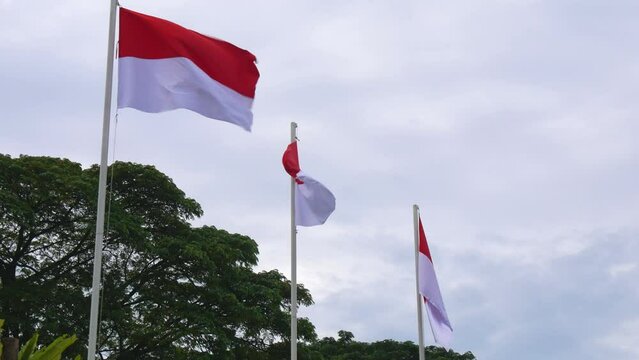The red and white Indonesian flags fluttering in the cloudy sky