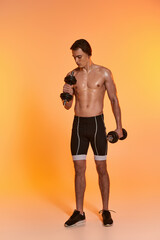 good looking muscular shirtless man in black sport shorts training with dumbbells on vivid backdrop