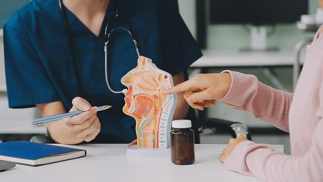 asian female doctor wearing face mask is showing a rectal model and explaining to elder senior man patient in hospital.