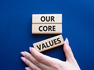 Our core values symbol. Concept words Our core values on wooden blocks. Beautiful deep blue background. Businessman hand. Business and Our core values concept. Copy space.