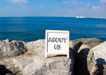 About us symbol. Concept word About us on white chalk background. Beautiful sea background....
