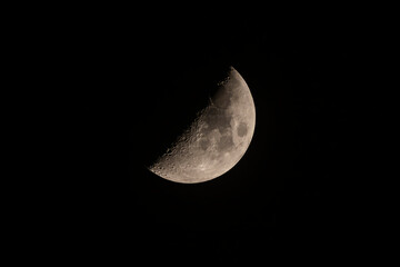 Media luna durante la fase del primer cuarto aislada contra un cielo negro.