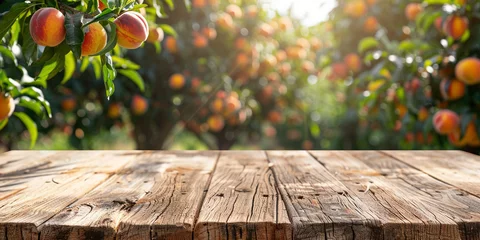 Poster Empty wooden kitchen table over peach fruit garden background © Ricardo Costa