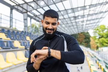 Active man checking fitness tracker at stadium