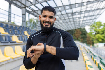 Smiling athlete checking time on smartwatch at stadium