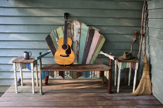 Acoustic guitar rests on a repurposed bench on a front porch