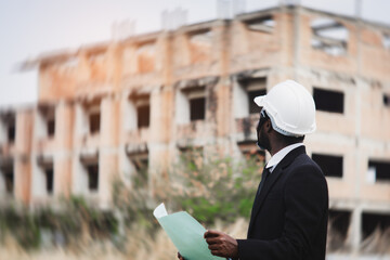 African engineer manager checking blueprint for demolition construction plan and rebuild at the site