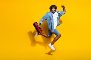 Full body photo of attractive young man raise fast excited boombox wear trendy denim clothes red scarf isolated on yellow color background