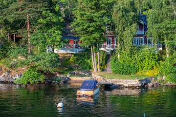 Stockholm Sweden Archipelago. Seafront villa, moored vessel, lush nature background.