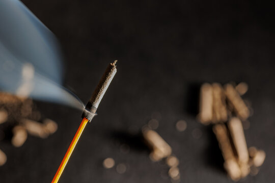 A closeup of incense stick with its colored fume on a black textured background with bokeh effect for graphic and web design use