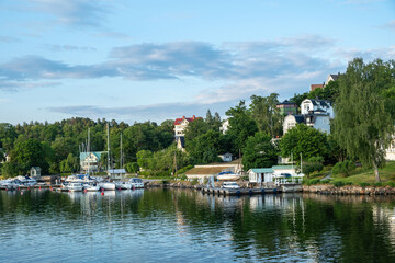 Fototapeta na wymiar Archipelago, Stockholm Sweden. Seafront villa, yacht, reflection in ripple water, cloudy sky.