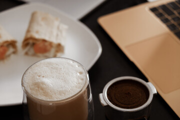 coffee on the desktop near the laptop . lunch at work