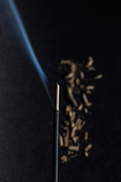 A closeup of incense stick and its blue fume on the grey textured background for graphic and web design use