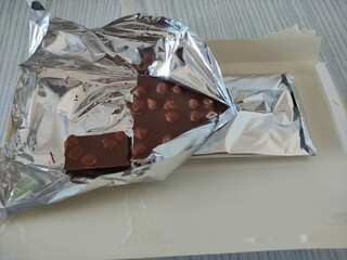 Chocolate with hazelnuts in foil and packaging, partially opened