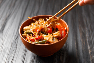 Buckwheat noodles with vegetables and chicken meat on a dark background.