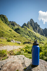  Reusable Blue Water Bottle on Rustic Wooden Surface with Alpine Background - 763379410