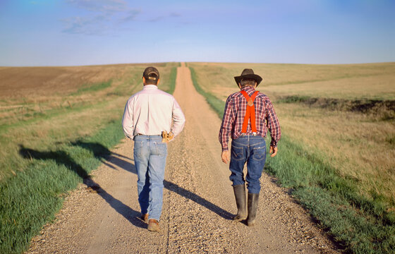 Rancher and his son walk down a gravel road; Howes, South Dakota, United States of America