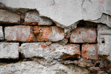 A red brick wall partially covered with crumbling plaster as an abstract, textural background.