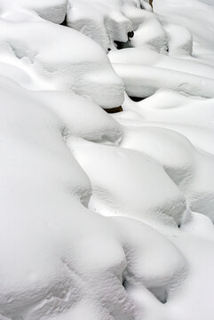 Close-up of snow covered rocks creating a contoured snow scene along a cliff; Lake Louise, Alberta, Canada
