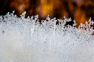Extreme close up of frost patterns on glass with a glowing background at sun rise; Calgary, Alberta, Canada