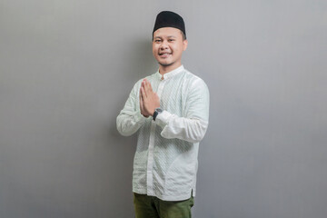 Asian Muslim man standing with Eid greeting gesture and welcoming Ramadan