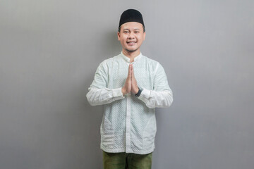 Asian Muslim man standing with Eid greeting gesture and welcoming Ramadan
