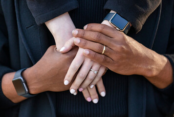 Close-up of the interlocked hands of a mixed race couple, spending quality time together during a fall family outing in a city park; Edmonton, Alberta, Canada