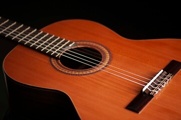 Fototapeta premium Classical Spanish flamenco guitar close up, dramatically lit isolated on black background with copy space.