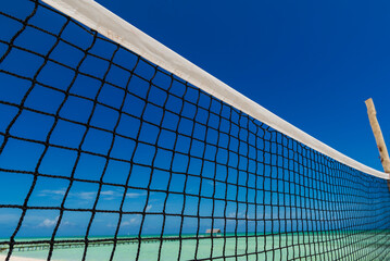 Close-up of the netting of a beach volleyball net against a blue sky and the Caribbean Sea; Cayo Guillermo, Cuba