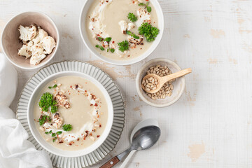 Cauliflower cream soup with pine nuts in a bowl on a white background