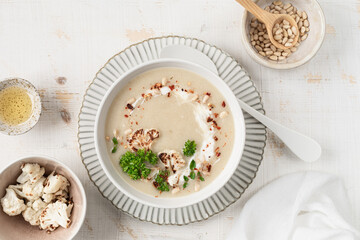Cauliflower cream soup with pine nuts in a bowl on a white background