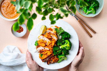 Women's hands hold a plate of chicken cutlet with katsu sauce.