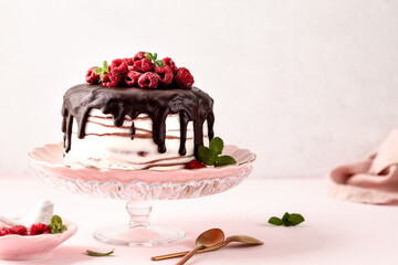 Pancake chocolate cake with fresh raspberries on a pink background.