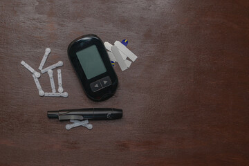 Flat lay of Diabetes glucometer for checking blood sugar, with test strips and lancets on wood...