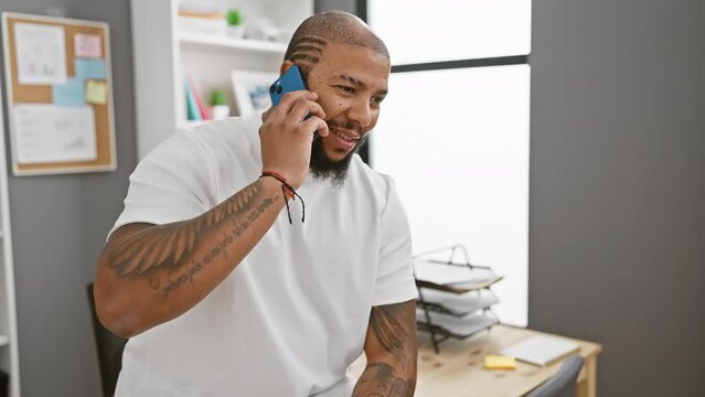 Smiling african american man with beard talking on phone in modern office setting