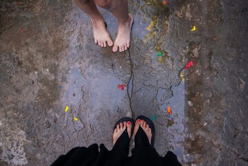 Pies de niño y pies de mujer en plano cenital con el piso mojado jugando al carnaval con bombitas...