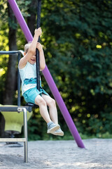 Cute kid on rope swing in summer in green park