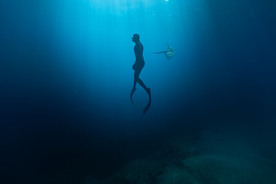 Fototapeta Freediver Swimming in Deep Sea With Sunrays. Young Man Diver Eploring Sea Life.