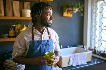 Fototapeta na wymiar Man Wearing Apron Working In Sustainable Plastic Free Store Having Coffee Break