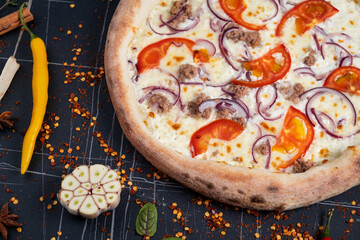 Seafood Italian pizza with tuna fillet, onions, fresh herbs and mozzarella on tomato served uncut on a crusty base viewed from above