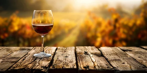 Cercles muraux Vignoble Wood table top with a glass of red wine on blurred vineyard landscape background